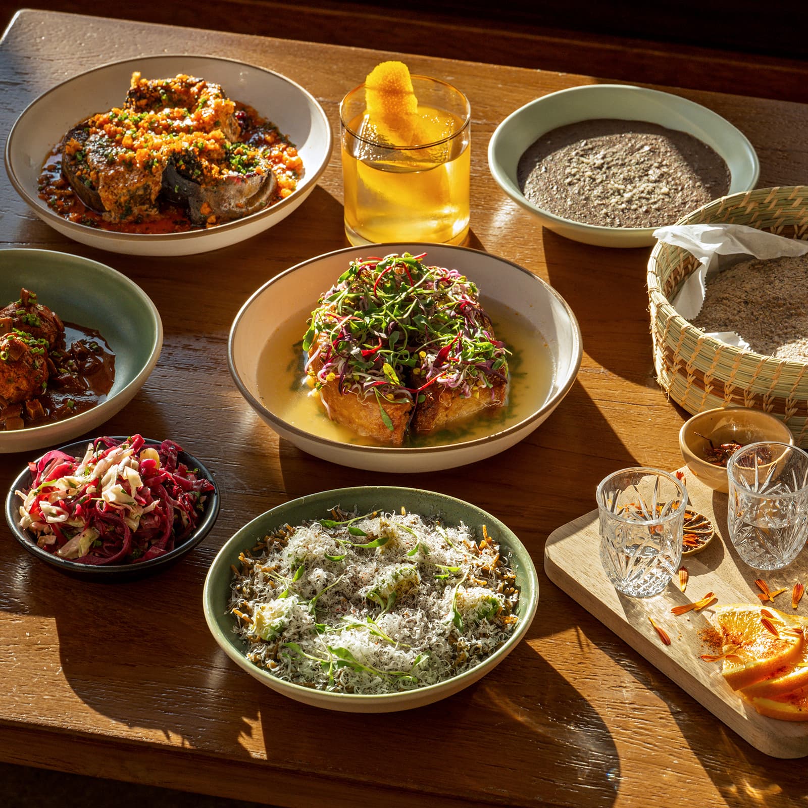 A stylish Los Angeles restaurant table set with small plates, candles, and cocktails