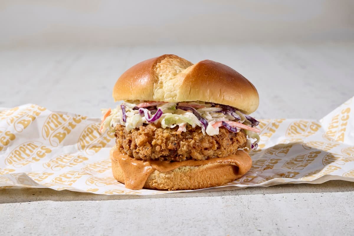 A cozy neighborhood restaurant table with fried chicken sandwiches, cocktails, and warm light in Del Ray