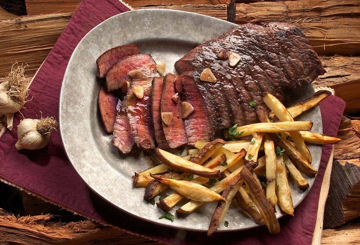 Dark moody steakhouse interior with dramatic lighting and elegant plating